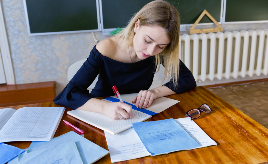 Una estudiant escrivint en uns papers damunt una taula